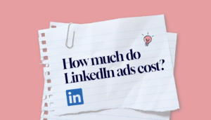 On a white piece of paper with the LinkedIn logo and a shining light bulb, the text reads, "How much do LinkedIn ads cost?"